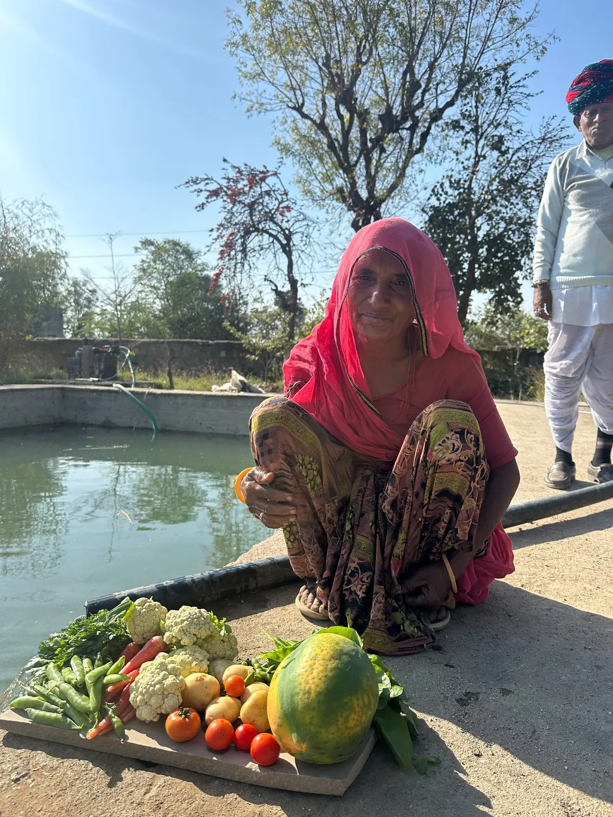 A farm worker beside a colourful harvest at Bholi Farm