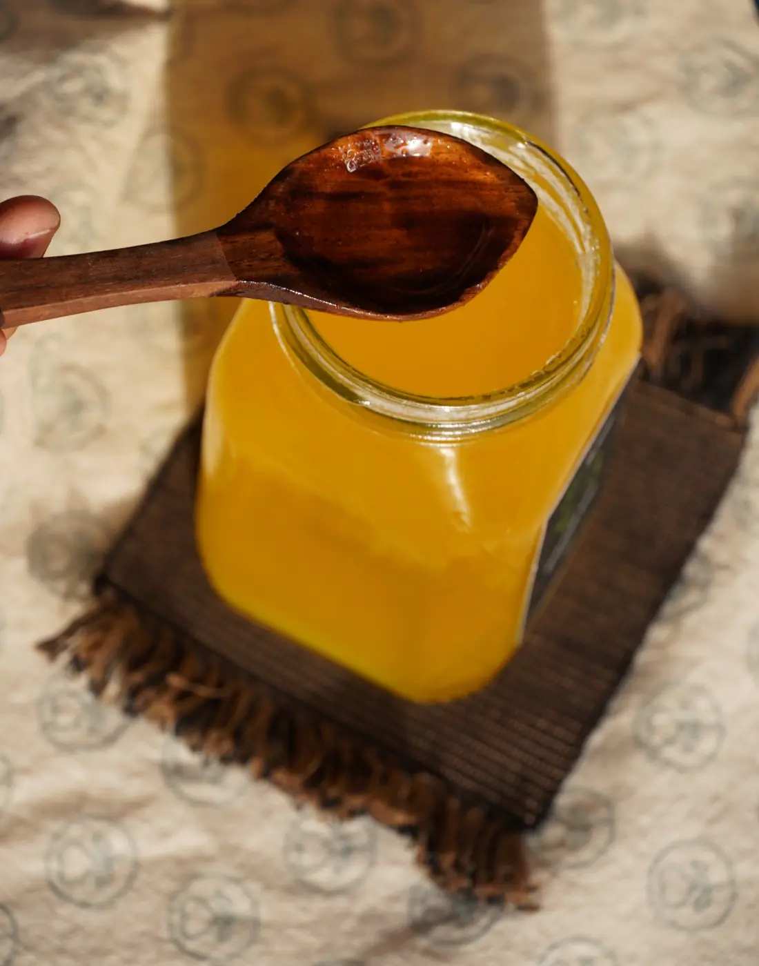 Farm-made ghee in a glass jar with a wooden spoon